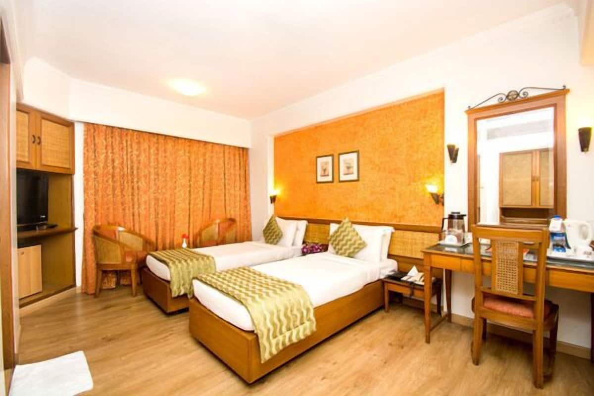 A hotel room with two beds, a desk, a chair, a television, and a mirror.