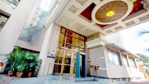 Un edificio moderno con entrada de vidrio, un tragaluz circular y una escalera que conduce a la entrada.