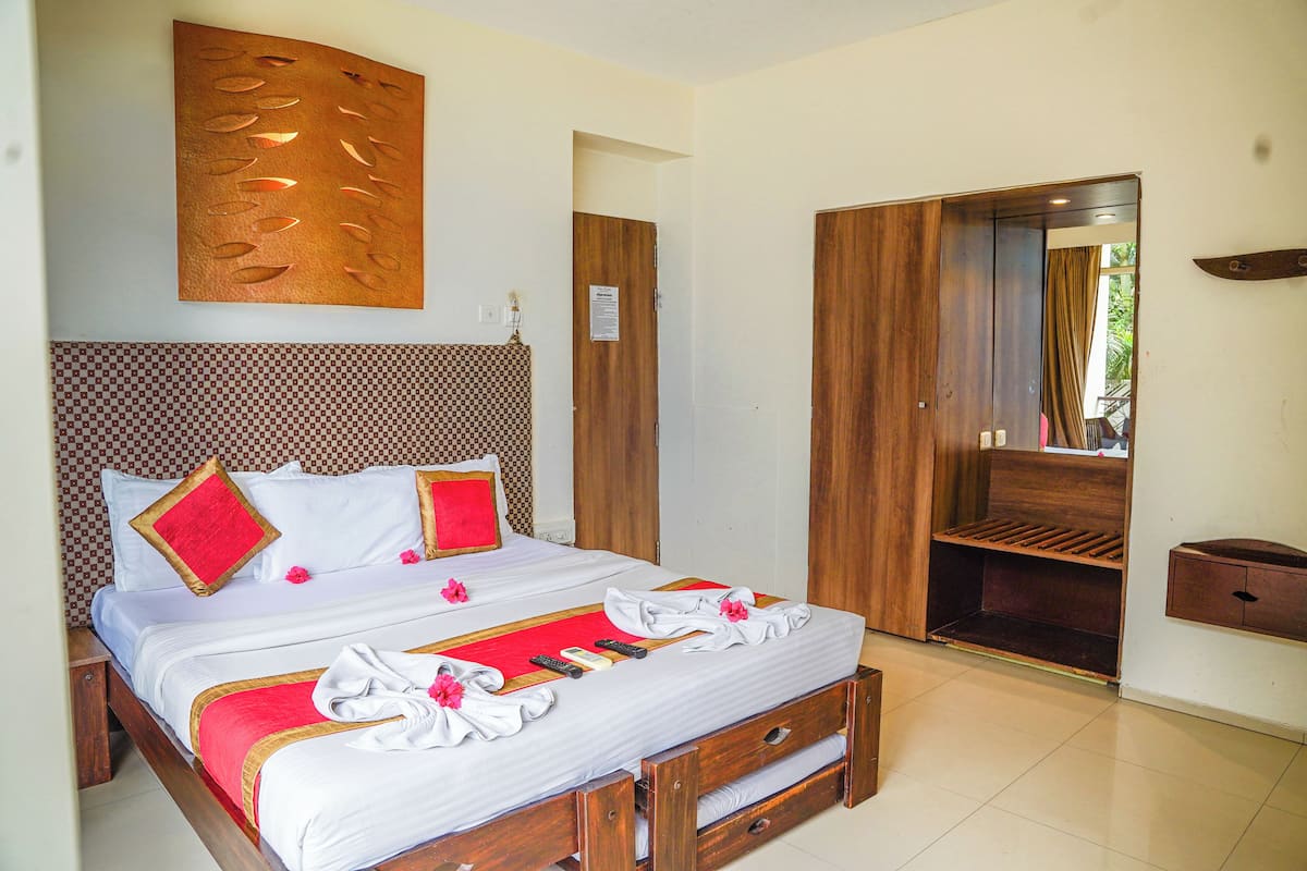 Una habitación de hotel con una cama grande, cabecera de madera y un armario.