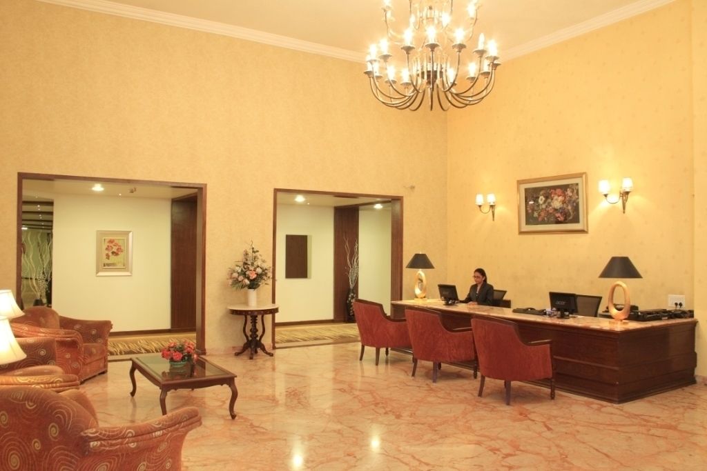 A lobby with a reception desk, chairs, a coffee table, and a chandelier.