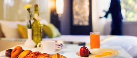 Una mesa de desayuno con pasteles, un vaso de zumo de naranja y un plato con huevos.
