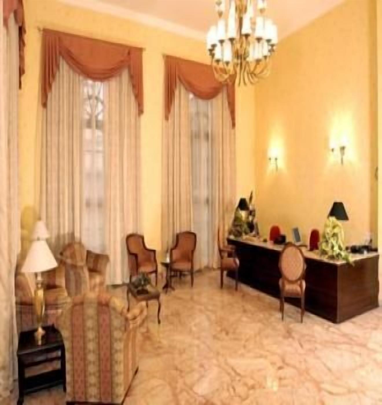 Un vestíbulo de hotel con una recepción, varias sillas, un sofá y una araña.