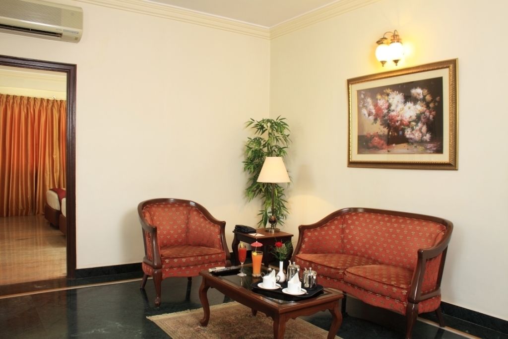 Une pièce comprenant deux fauteuils, une petite table sur laquelle se trouve un plateau avec divers objets, une lampe et un tableau accroché au mur.