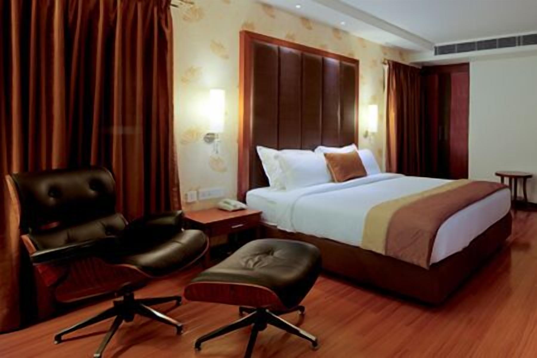 A hotel room with a large bed, a desk, a chair, and a small table.