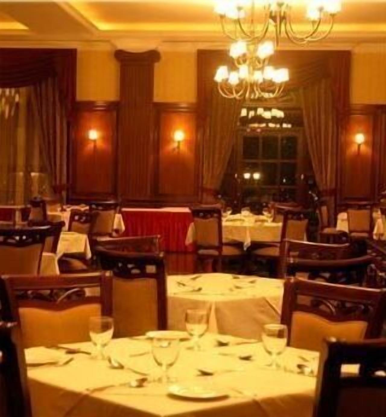 A restaurant with multiple tables, chairs, and a chandelier.