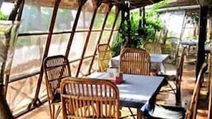 An outdoor dining area with wooden chairs and tables, covered by a transparent roof. - Angels Resort (Alto de Porvorim)