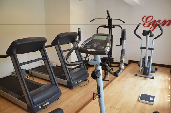 A gym with treadmills, an elliptical, and a stationary bike. - Sonesta Inn (Candolim)