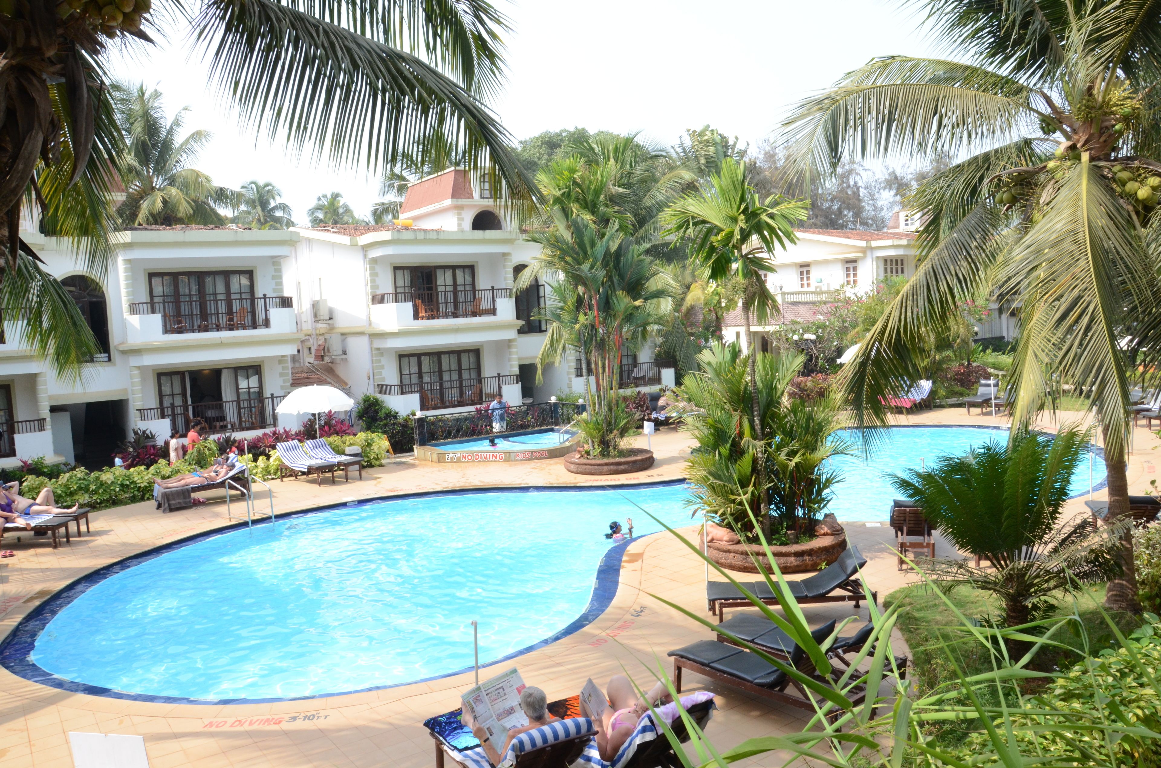A resort with a large swimming pool, palm trees, and lounge chairs.
