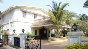 A white building with a curved facade, a covered entrance, and a gated driveway.
