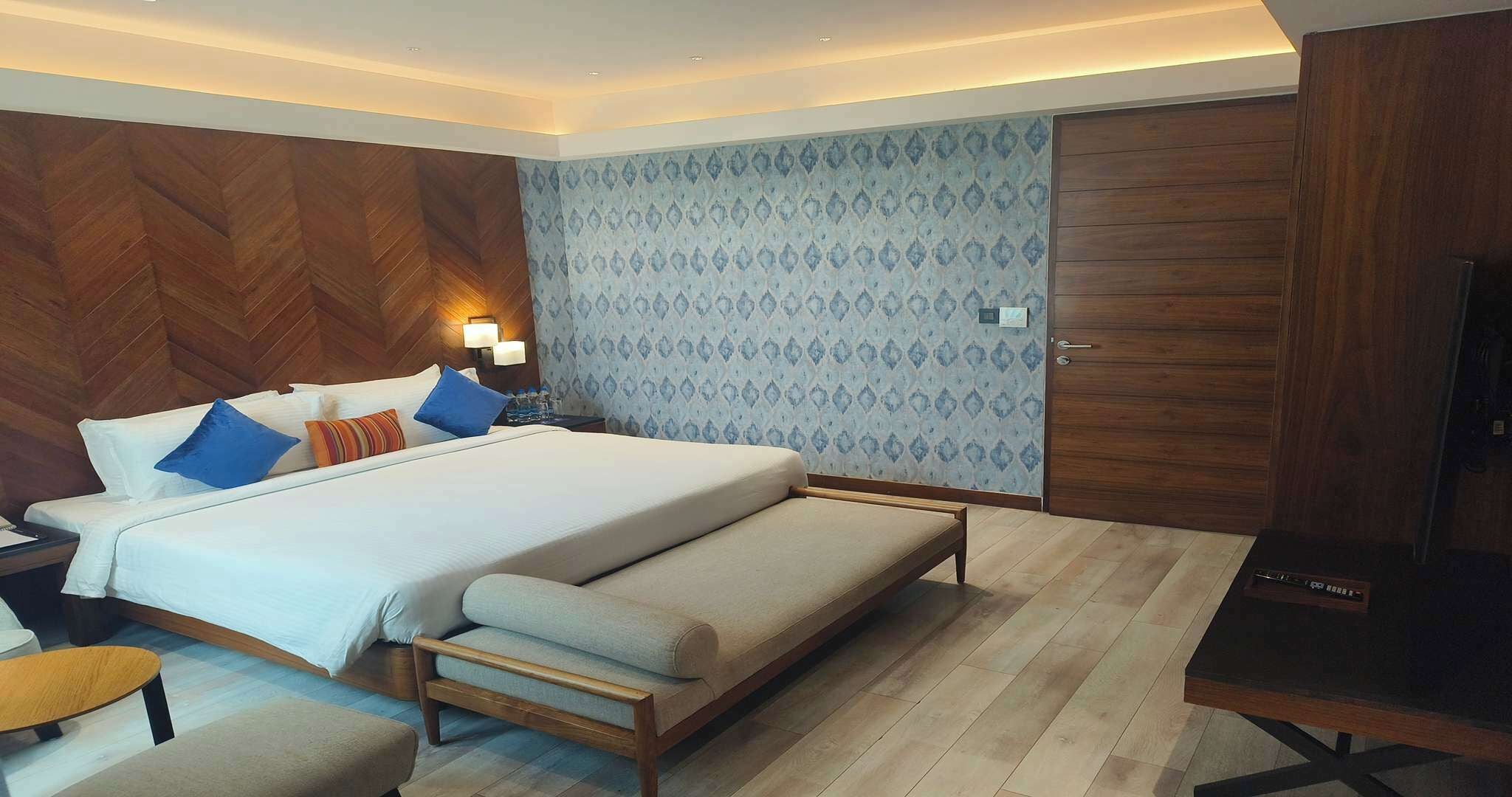 Une chambre d’hôtel moderne avec un grand lit, un banc, un bureau et une armoire.