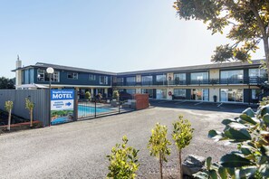 Un motel con piscina, zona de recepción y aparcamiento vallado.