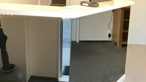 Una habitación con un escritorio blanco, un cuadro en la pared y una escalera que conduce a otra habitación.