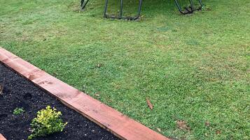 Enjoy a fun-filled stay with a backyard featuring a trampoline and swing set amidst lush greenery.