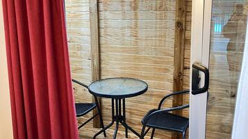 Een houten terras met een ronde tafel en twee stoelen.