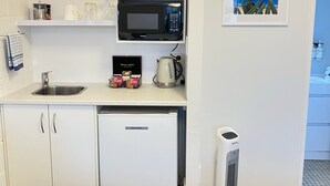 Una kitchenette compacta con microondas, tostadora y refrigerador pequeño.