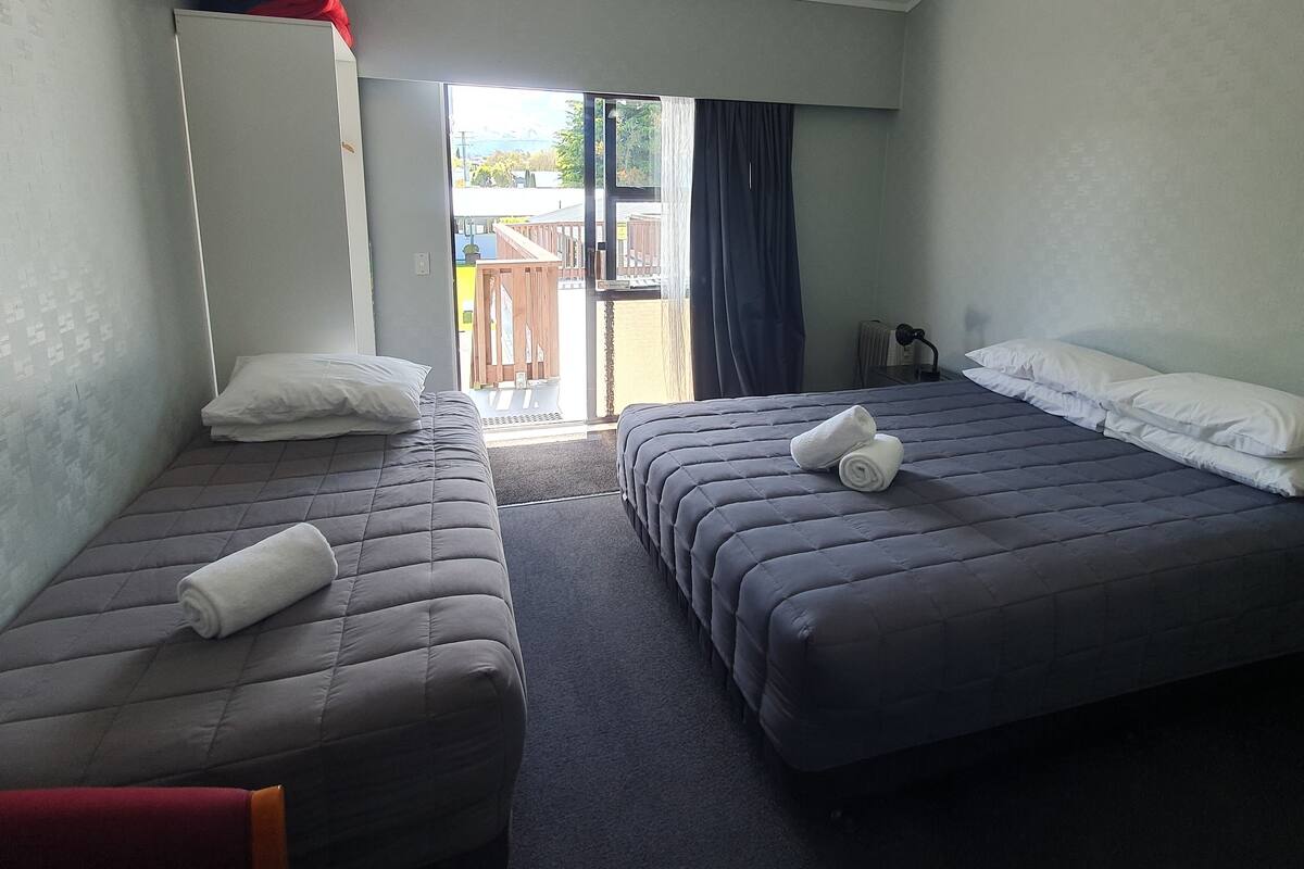 A hotel room with two beds, a ceiling light, and a view of the outside.