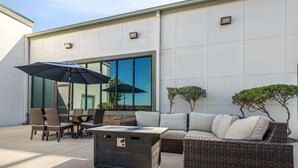 Ein Außenbereich mit Terrasse, Essbereich, Tisch, Stühlen, einer Couch und einem Sonnenschirm.