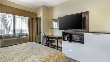 Une chambre d’hôtel équipée d’un lit, d’un bureau, d’une télévision, d’un four à micro-ondes et d’un mini-bar.