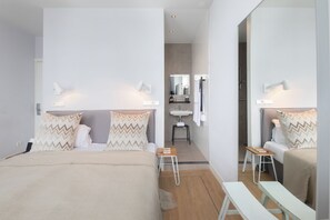 A modern bedroom with a bed, bedside tables, a mirror, and a bathroom visible through an open door. - Stadsvilla Hotel Mozaic Den Haag (The Hague)