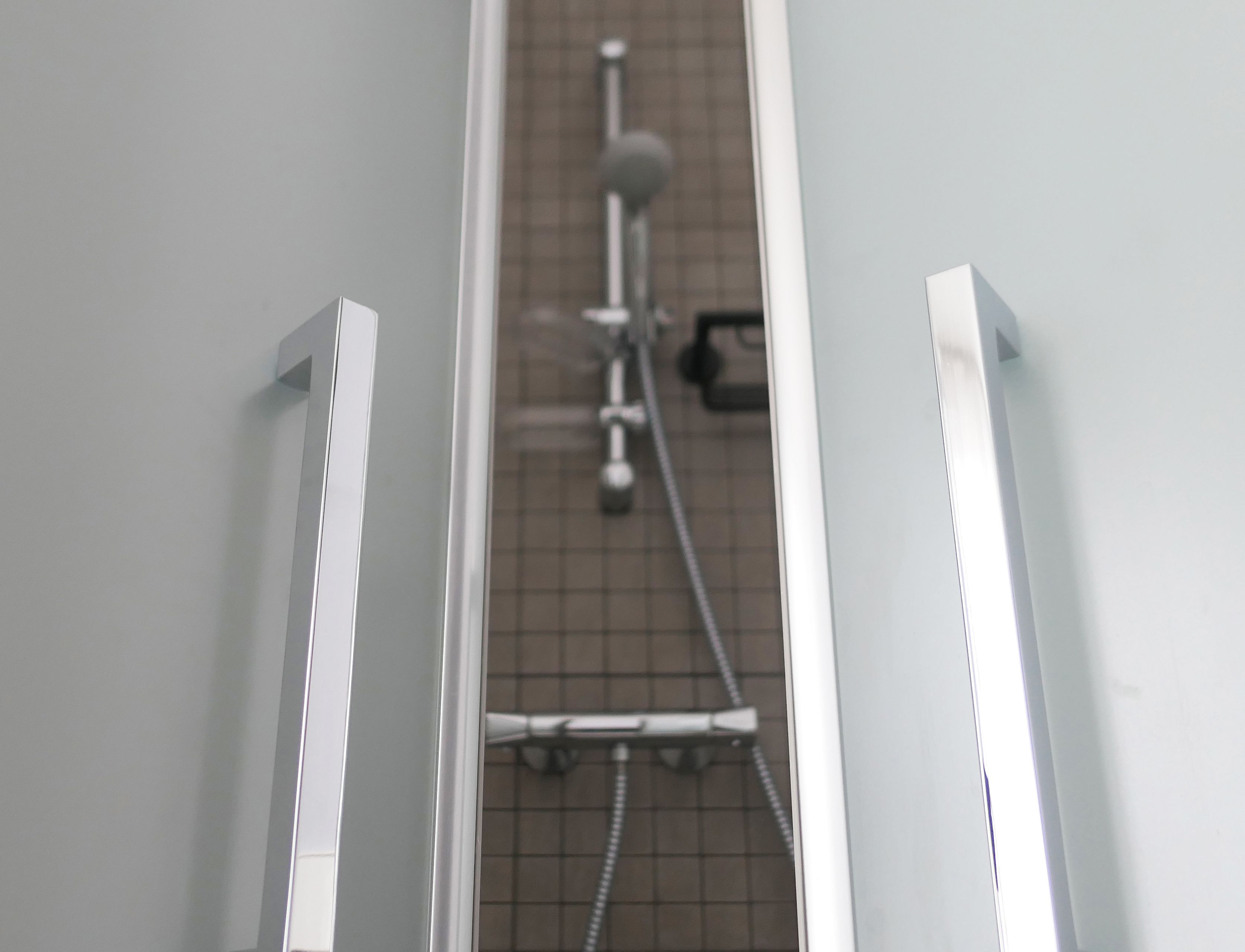 Un espace douche doté d’un sol carrelé et d’un pommeau de douche à main.