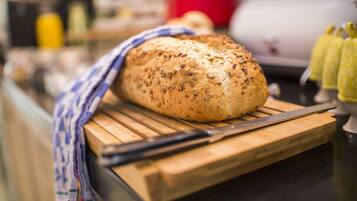 A loaf of bread on a wooden cutting board with a knife beside it.