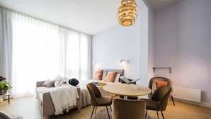 Ett modernt vardagsrum med en soffa, fåtöljer, ett runt bord och en hängande lampa.