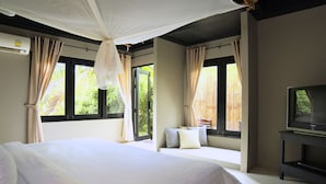 Un dormitorio con una cama grande, un televisor en un mueble bajo y ventanas con cortinas.