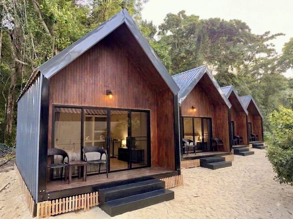 A row of wooden cabins with sliding glass doors, each with a small outdoor seating area.