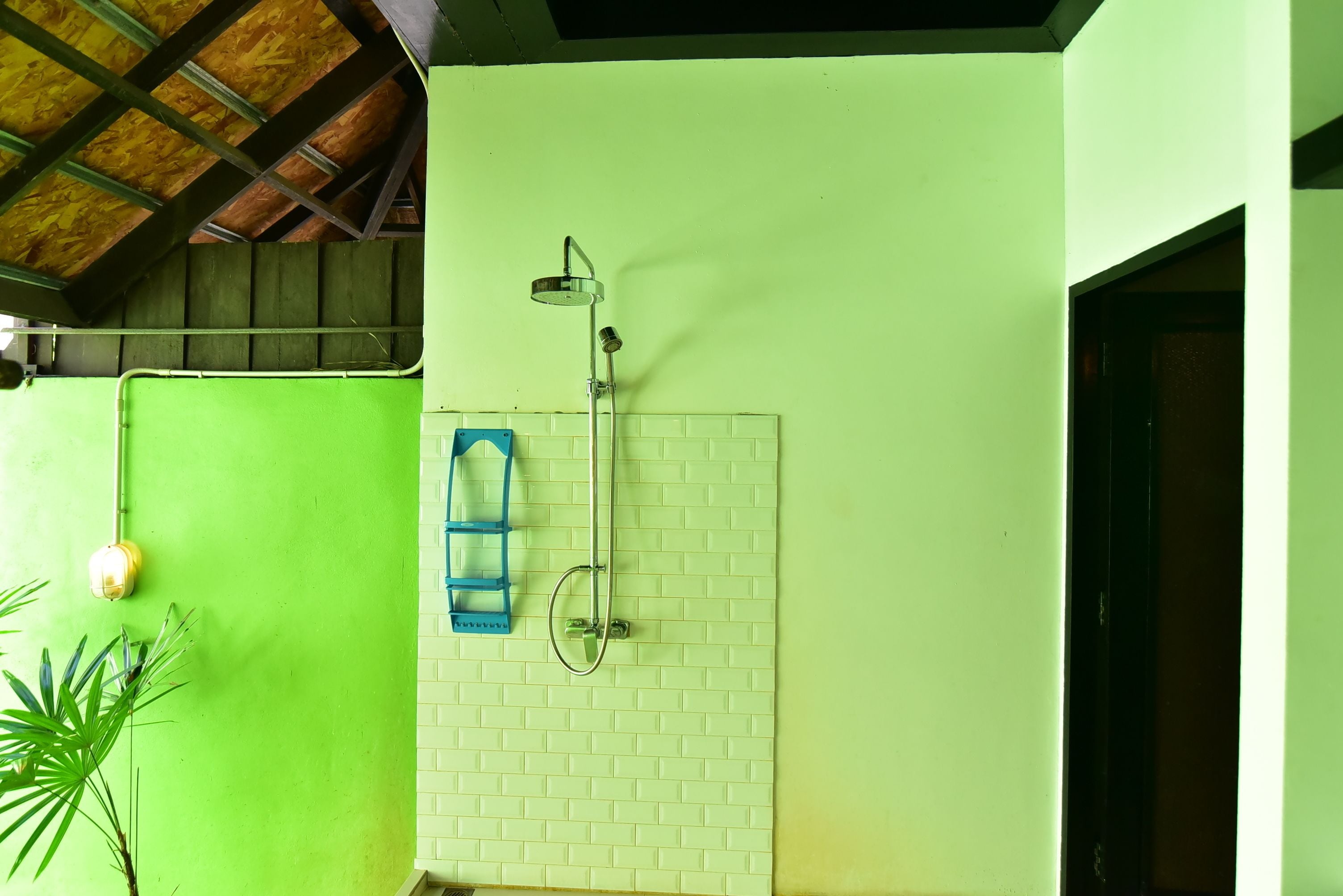 Un baño con ducha, una escalera azul y una pared verde.