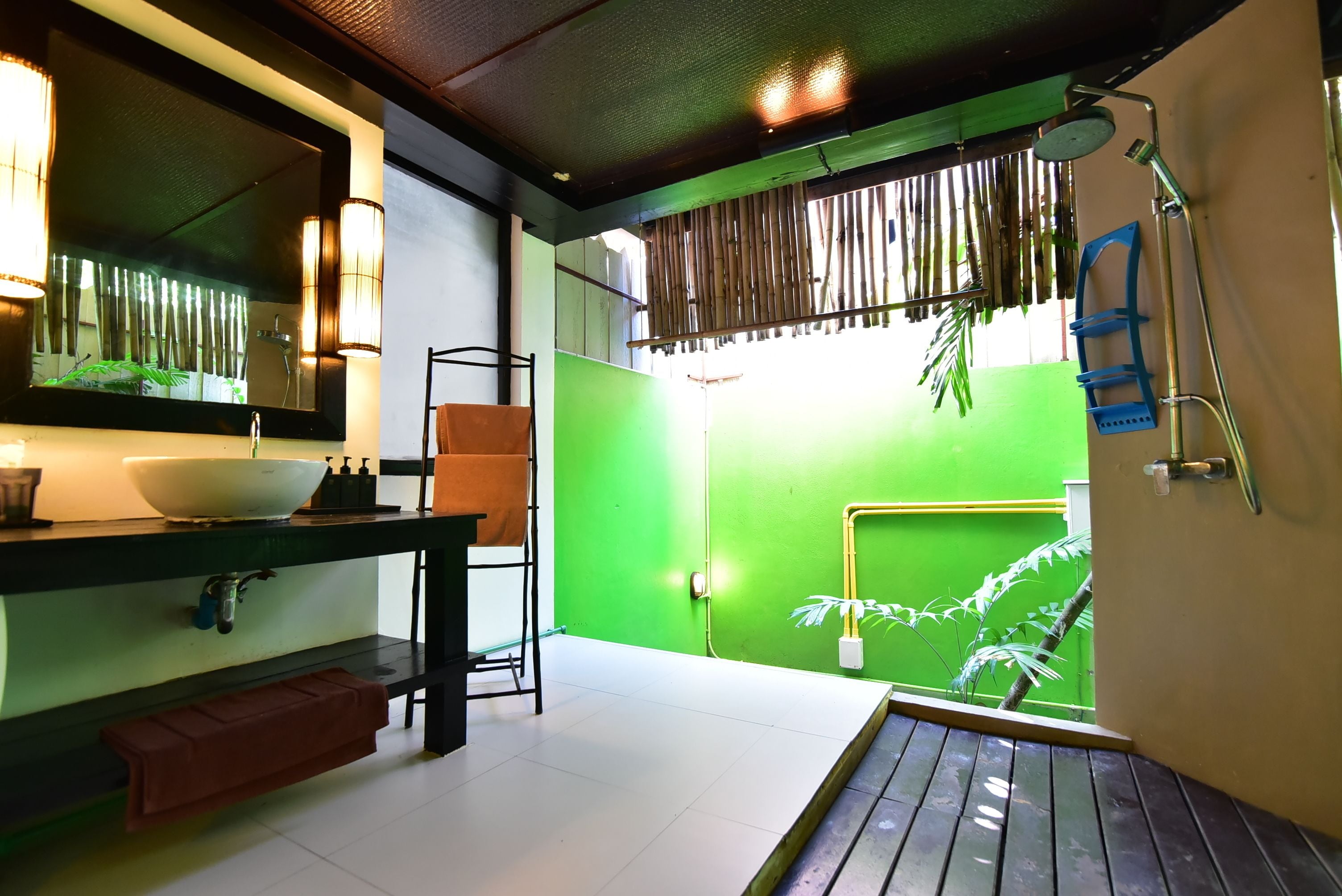 A bathroom with a green wall, a white sink, a mirror, and a shower area.