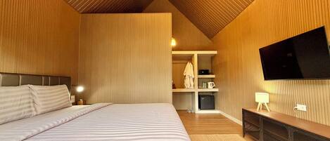 A bedroom with a large bed, a flat-screen TV mounted on the wall, and a built-in bench with storage.