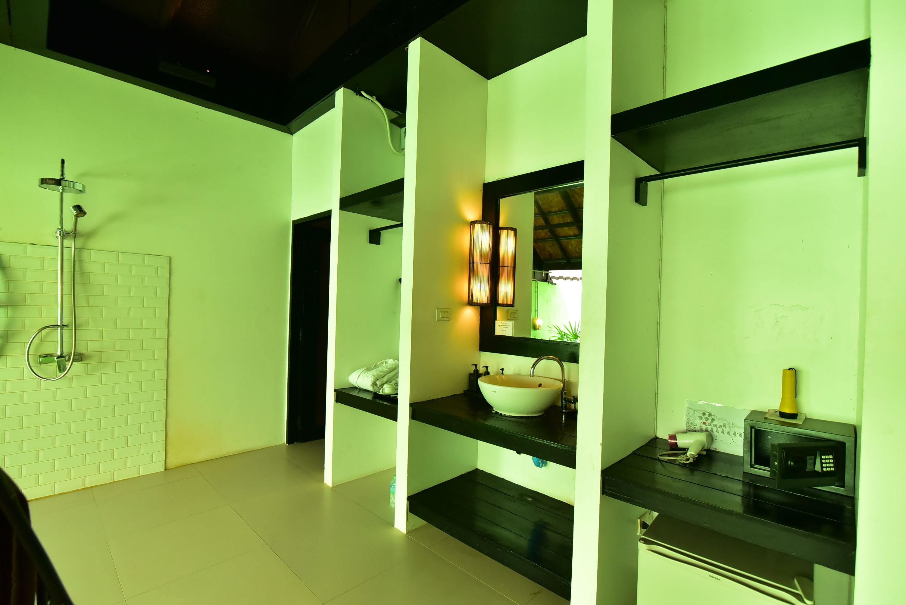 A modern bathroom with a white sink, black countertop, and a shower with a glass door.