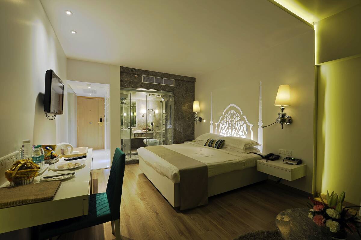 Una habitación de hotel con cama, mesita de noche, lámpara y un escritorio con silla.