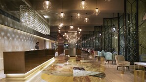 Eine moderne Lobby mit Empfangstresen, Sitzgelegenheiten und dekorativer Beleuchtung.