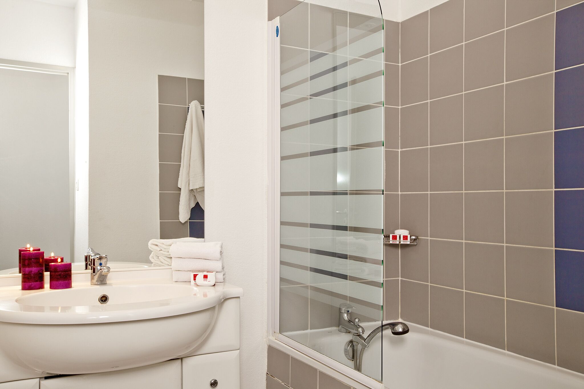 A bathroom with a sink, mirror, and shower.