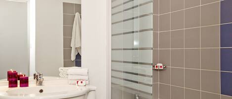 A bathroom with a sink, mirror, and shower.
