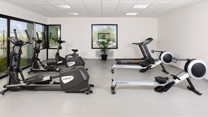 Een sportschool met hometrainers, loopbanden en een roeimachine.