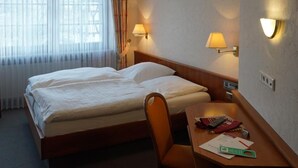 Una camera d'hotel con un letto, una scrivania e due lampade a parete.