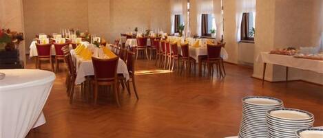 A banquet hall with multiple round tables set for dining, arranged in rows.