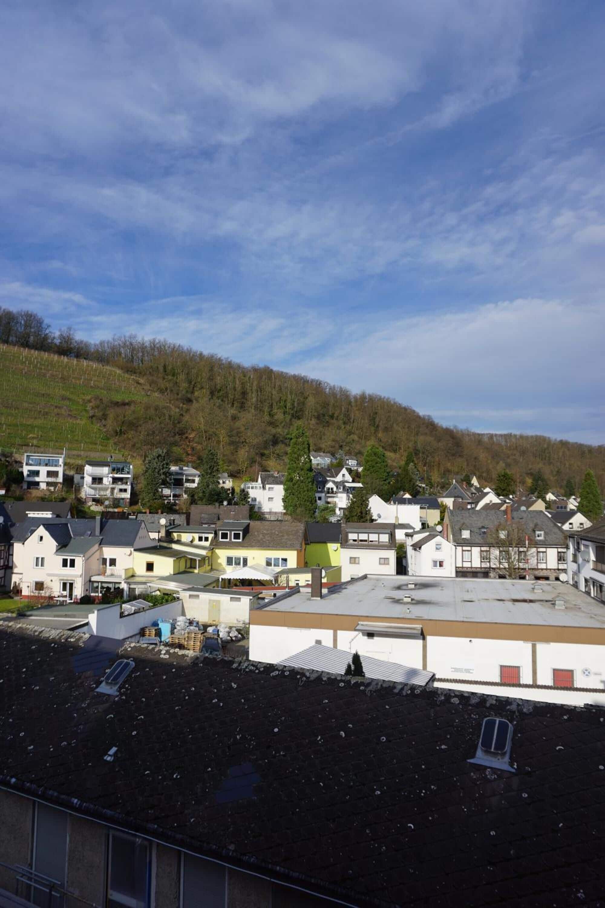Un barrio residencial con casas, una colina al fondo y cielo despejado.