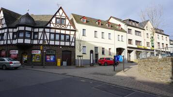 Una calle europea tradicional con un edificio de entramado de madera y un edificio moderno blanco con un letrero de restaurante.