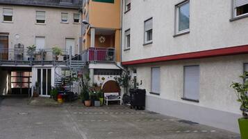 A courtyard with a hotel entrance, potted plants, and a staircase leading to an upper level.
