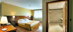 A hotel room with a bed, bedside table, lamp, and a view of the bathroom. - Hotel Torre DE Sila (Tordesillas)