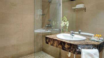 Un baño moderno con ducha de vidrio, lavamanos de mármol y un espejo grande.