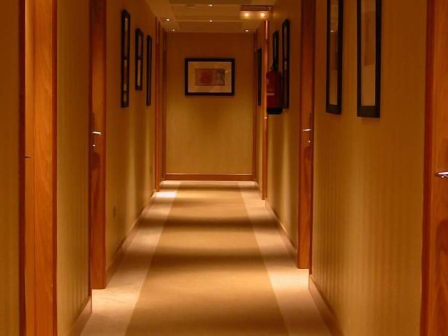 A hotel hallway with wooden doors and framed pictures on the walls.