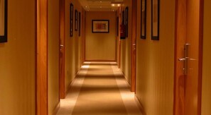 A hotel hallway with wooden doors and framed pictures on the walls. - Hotel Torre DE Sila (Tordesillas)