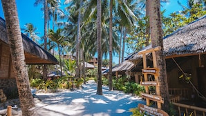 A pathway lined with palm trees leading to a resort area with thatched-roof buildings and wooden signs indicating amenities like a shower, reception, and conference room. - Fridays Boracay Resort (Boracay Island)