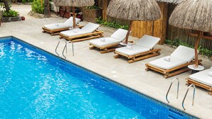 A swimming pool with lounge chairs and thatched umbrellas. - Fridays Boracay Resort (Boracay Island)