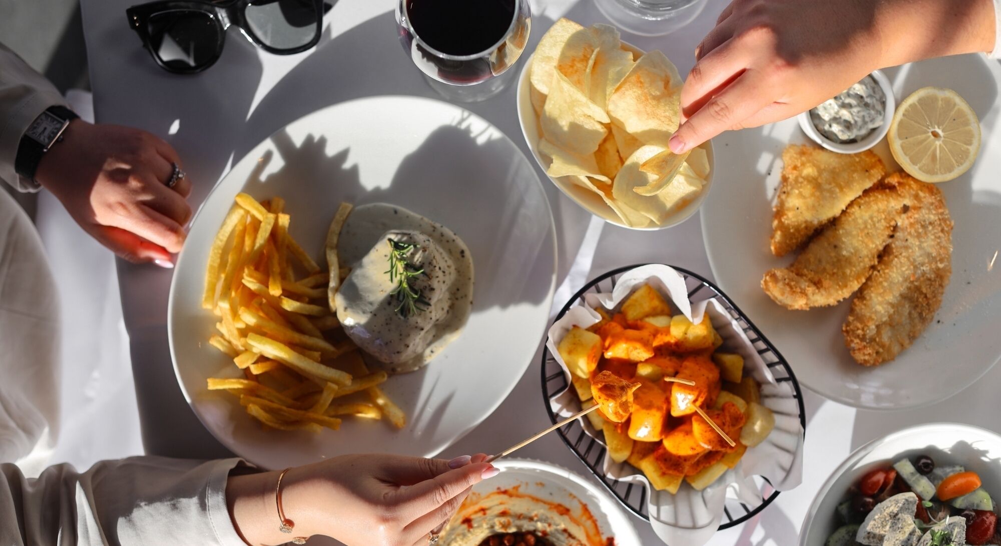 A table with various dishes including fries, a fish dish, and a dessert.