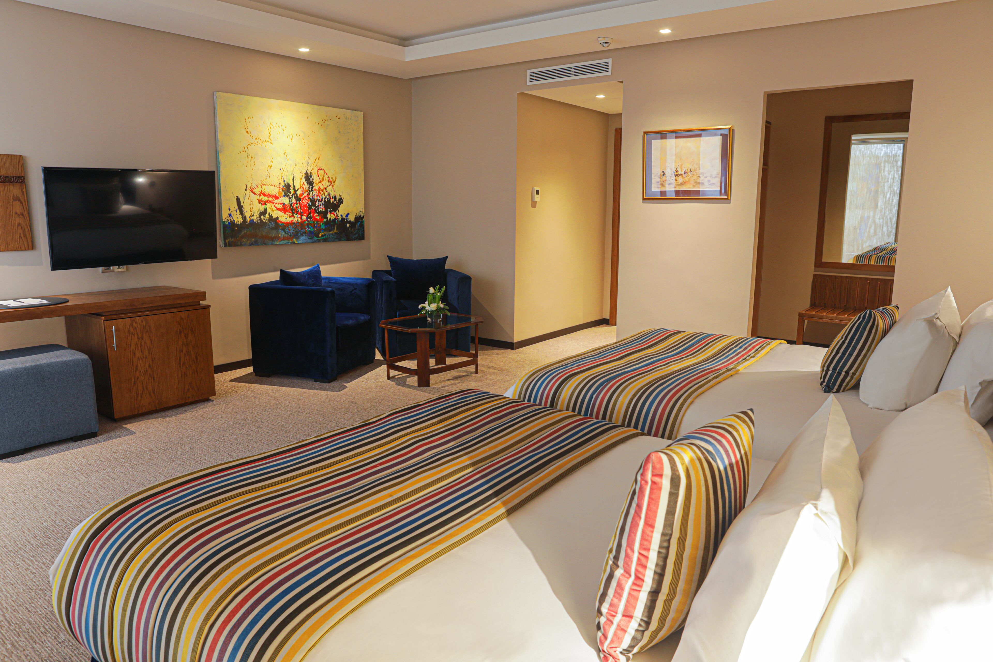 A hotel room with two beds, a TV, a desk, and a chair.
